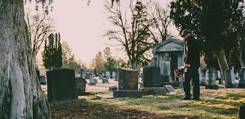 man in hat with flowers in cemetery